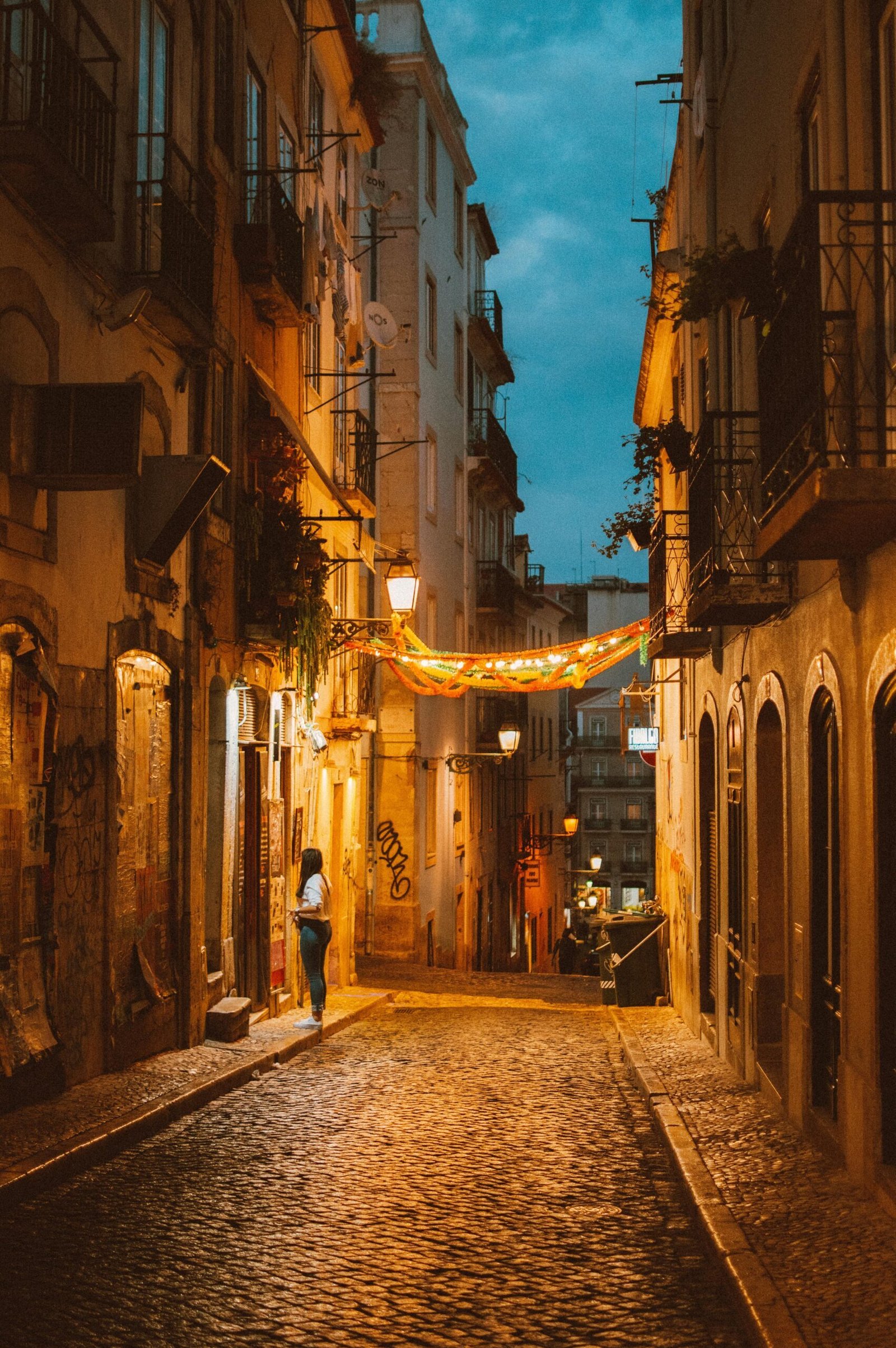 Discover the enchanting charm of a narrow street in Lisbon at dusk, capturing the essence of Portugal's architectural beauty.