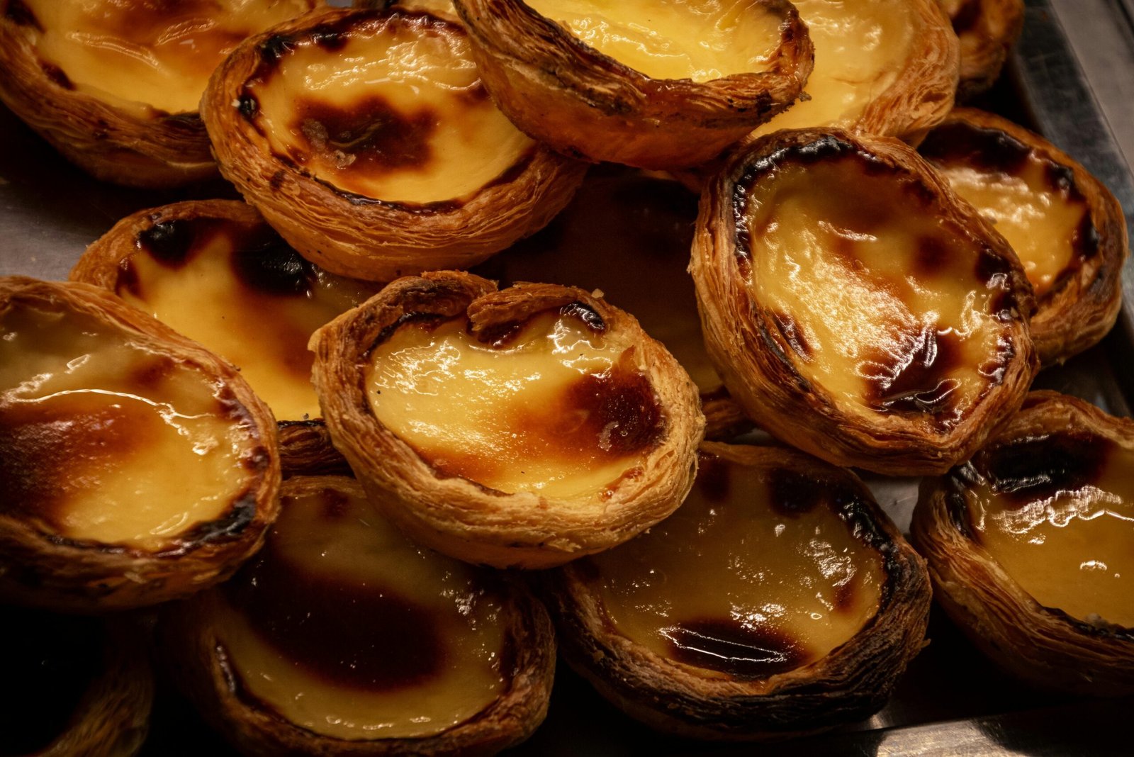 A tempting display of traditional Portuguese Pastel de Nata pastries, glistening with caramelized tops.
